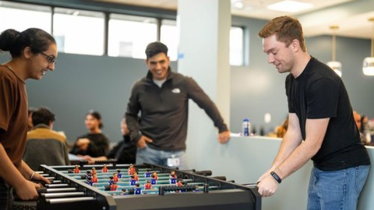Photos shows students playing foosball in the student lounge. 