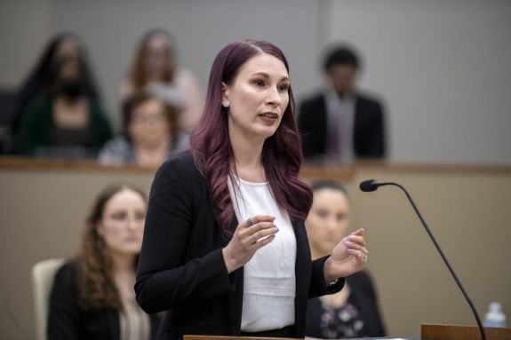 A female student argues a case at a podium in the courtroom