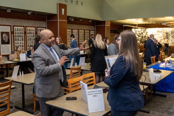 Man in grey suit talks with a student