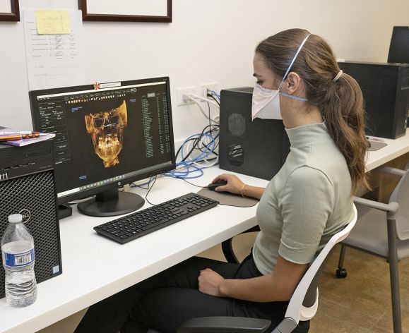 woman sitting at computer looking at orthodontics imaging