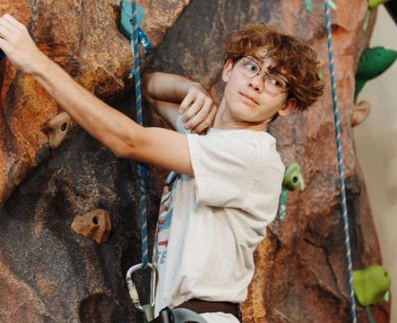 a student climbing the rock wall in baun fitness center